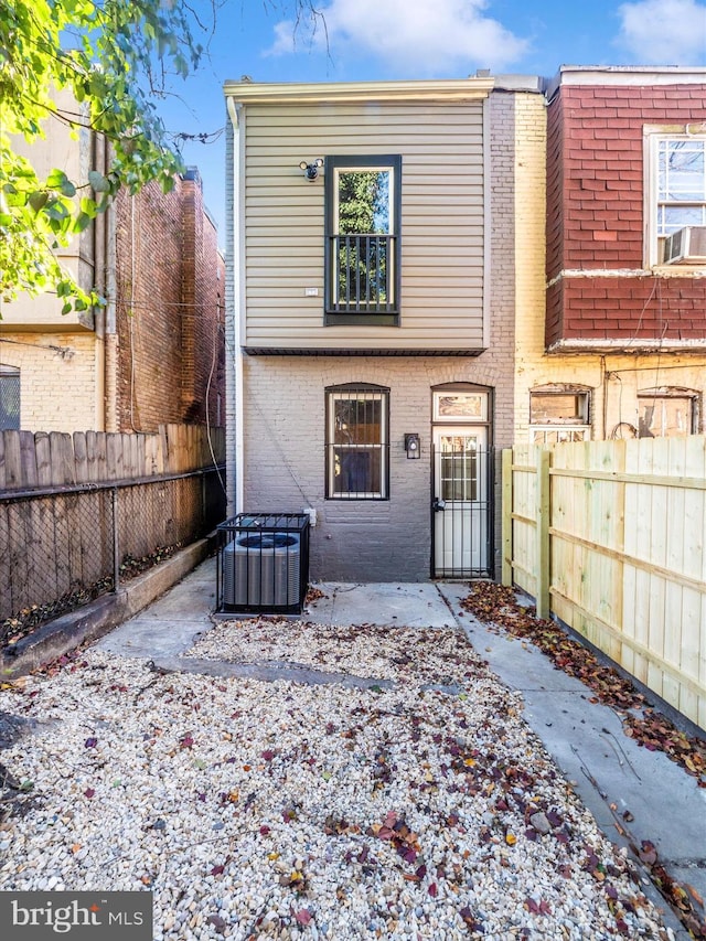 310 E 25th St, Baltimore, MD 21218 - rear view of property featuring central air condition unit, a fenced backyard, brick siding, and cooling unit