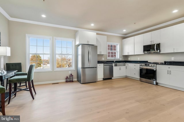 kitchen featuring crown molding, light hardwood / wood-style flooring, white cabinets, and stainless steel appliances