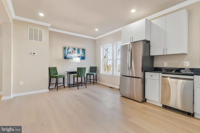 kitchen with light wood-type flooring, white cabinetry, ornamental molding, and appliances with stainless steel finishes