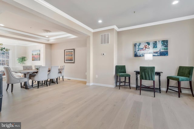 dining space with ornamental molding and light hardwood / wood-style flooring