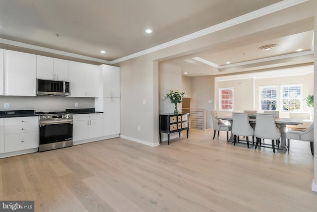 kitchen with light hardwood / wood-style floors, crown molding, white cabinetry, and stainless steel appliances