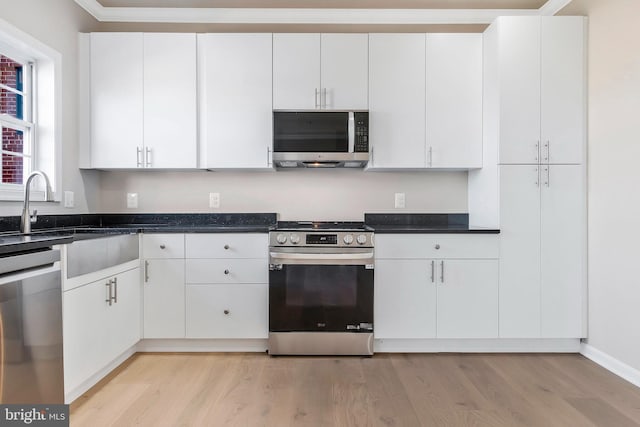 kitchen with light hardwood / wood-style flooring, white cabinets, and appliances with stainless steel finishes