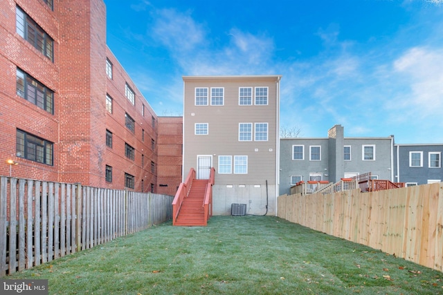 back of house featuring central AC unit and a yard