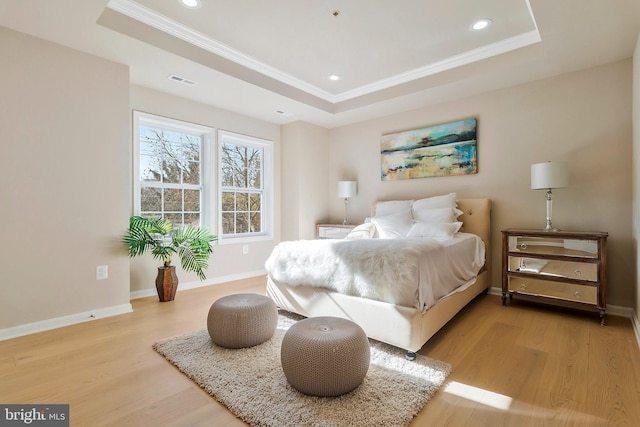 bedroom featuring a raised ceiling, light hardwood / wood-style flooring, and ornamental molding