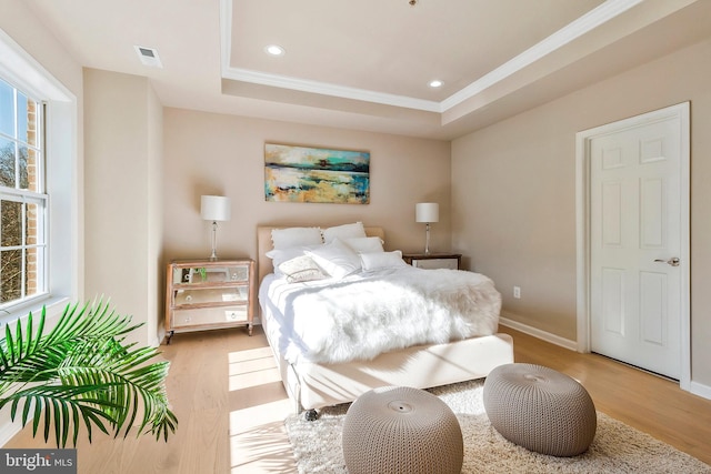 bedroom with a raised ceiling and light hardwood / wood-style flooring