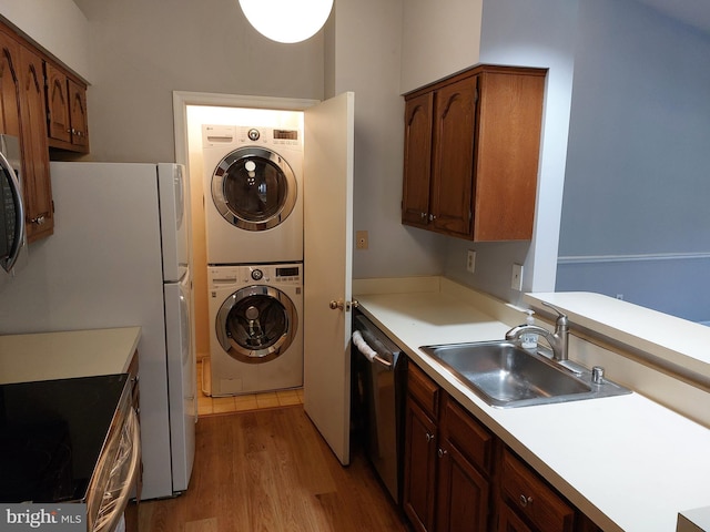 laundry room with stacked washer / dryer, light hardwood / wood-style flooring, and sink