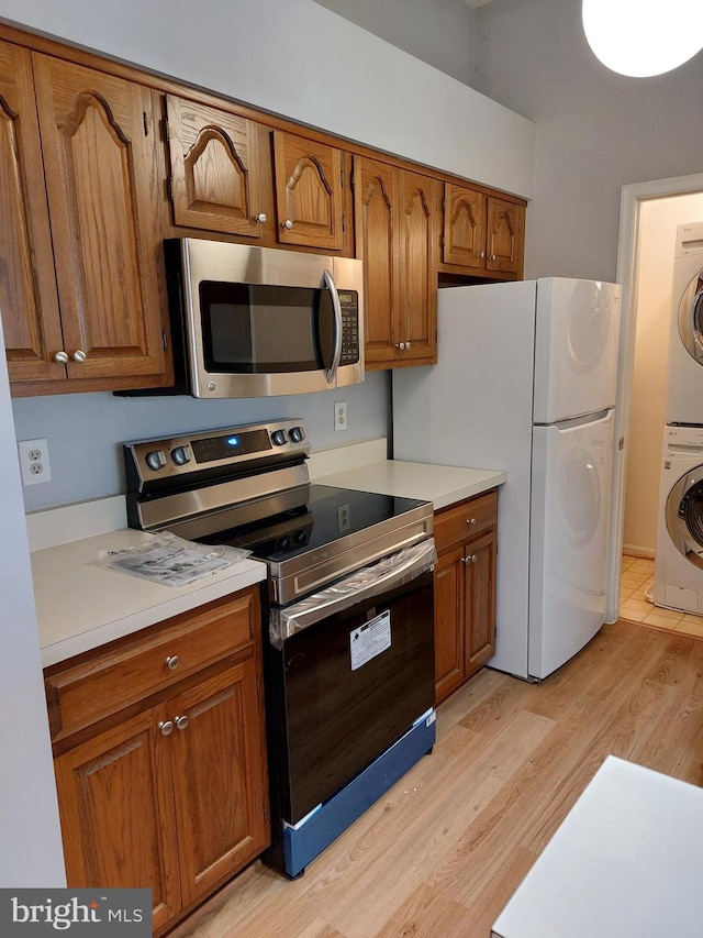 kitchen with stacked washer / dryer, appliances with stainless steel finishes, and light hardwood / wood-style flooring