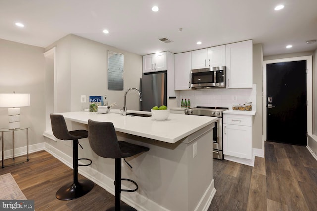 kitchen with white cabinetry, sink, dark wood-type flooring, a kitchen breakfast bar, and appliances with stainless steel finishes