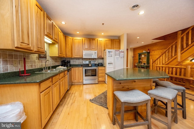 kitchen with backsplash, stainless steel appliances, sink, light hardwood / wood-style flooring, and a breakfast bar area