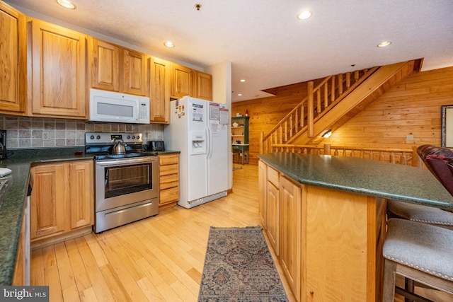 kitchen featuring a kitchen breakfast bar, tasteful backsplash, white appliances, a kitchen island, and wood walls