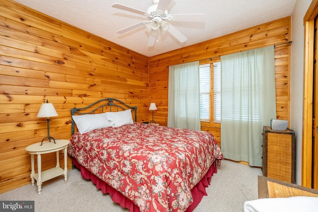 carpeted bedroom featuring ceiling fan, a textured ceiling, and wooden walls