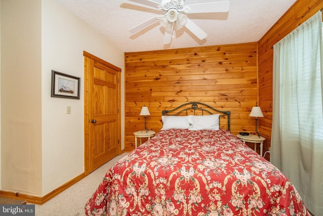 carpeted bedroom with ceiling fan, a textured ceiling, and wooden walls