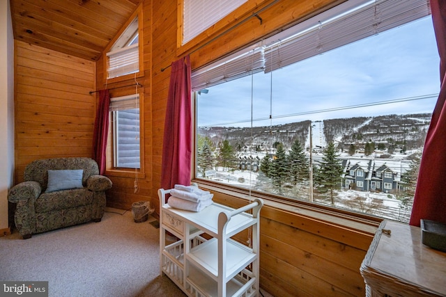 sitting room with wooden walls, carpet, a mountain view, and vaulted ceiling