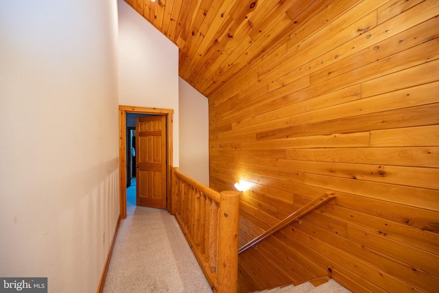 hallway with wood ceiling, lofted ceiling, light carpet, and wooden walls