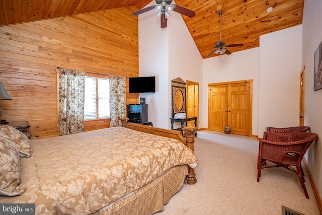 carpeted bedroom with ceiling fan, wooden walls, and high vaulted ceiling