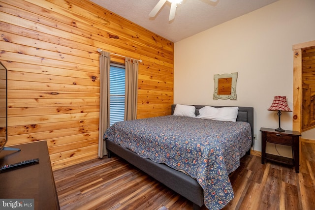 bedroom featuring a textured ceiling, ceiling fan, dark hardwood / wood-style flooring, and wood walls