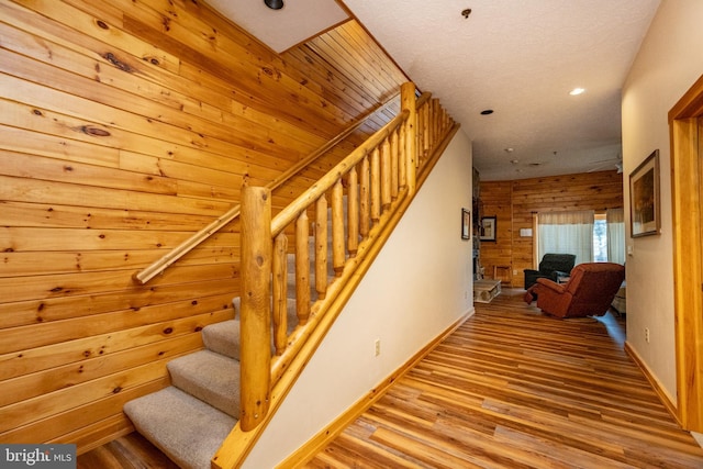 stairway with hardwood / wood-style flooring and wood walls