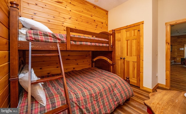 bedroom with hardwood / wood-style floors, wood walls, and a closet