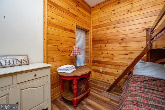 bedroom with light hardwood / wood-style floors and wood walls