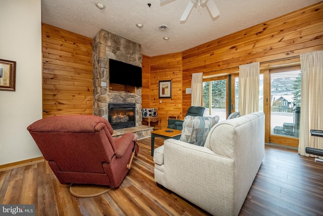 living room featuring hardwood / wood-style floors, ceiling fan, a textured ceiling, and wooden walls