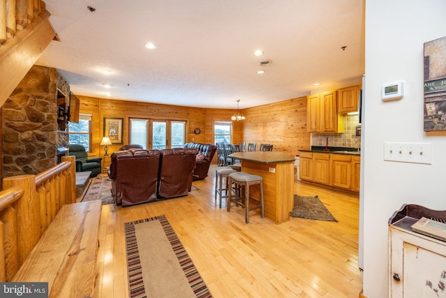 kitchen featuring tasteful backsplash, a kitchen bar, wooden walls, a kitchen island, and light wood-type flooring