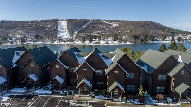 snowy aerial view featuring a water and mountain view