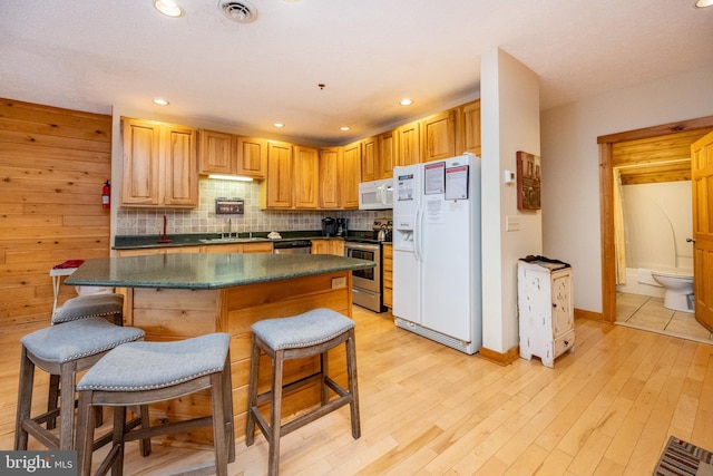 kitchen featuring sink, a kitchen breakfast bar, decorative backsplash, appliances with stainless steel finishes, and light wood-type flooring