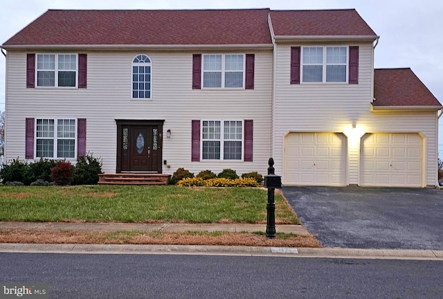 colonial home featuring a front yard and a garage