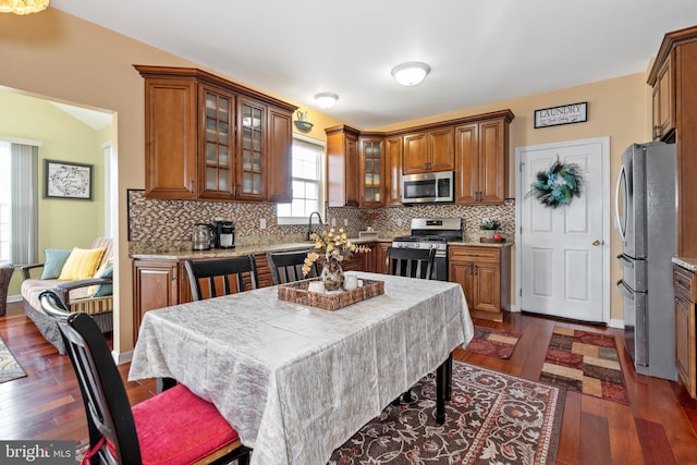 kitchen with sink, a center island, dark wood-type flooring, decorative backsplash, and appliances with stainless steel finishes