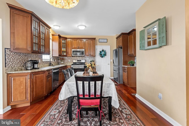 kitchen featuring sink, stainless steel appliances, tasteful backsplash, light stone counters, and dark hardwood / wood-style floors