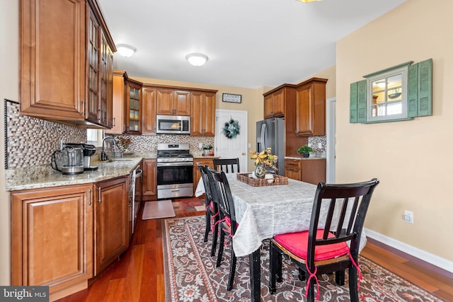 kitchen featuring sink, decorative backsplash, light stone countertops, dark hardwood / wood-style flooring, and stainless steel appliances