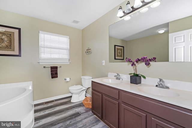 bathroom with a tub, vanity, wood-type flooring, and toilet