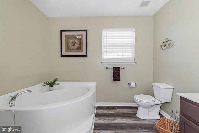 bathroom with hardwood / wood-style flooring, vanity, toilet, and a bathing tub