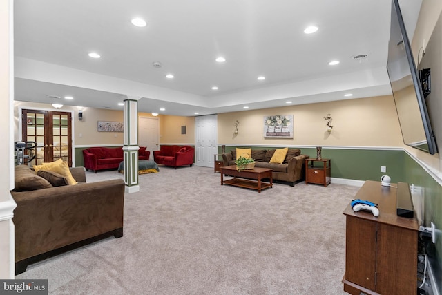 carpeted living room featuring a tray ceiling, ornate columns, and french doors