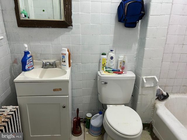 bathroom with a washtub, vanity, toilet, and tile walls