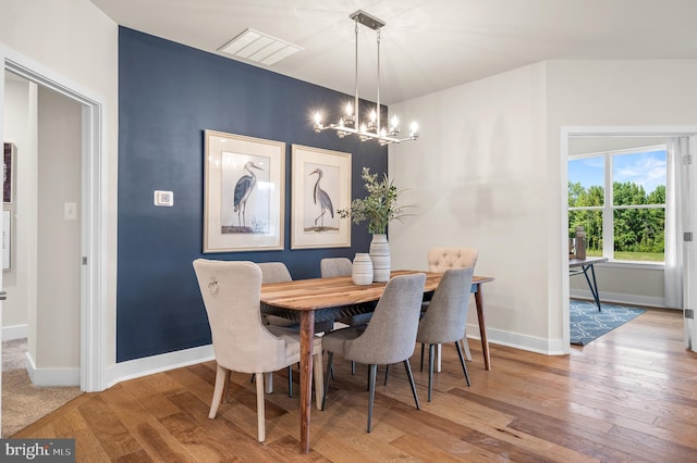 dining space featuring hardwood / wood-style flooring and a notable chandelier