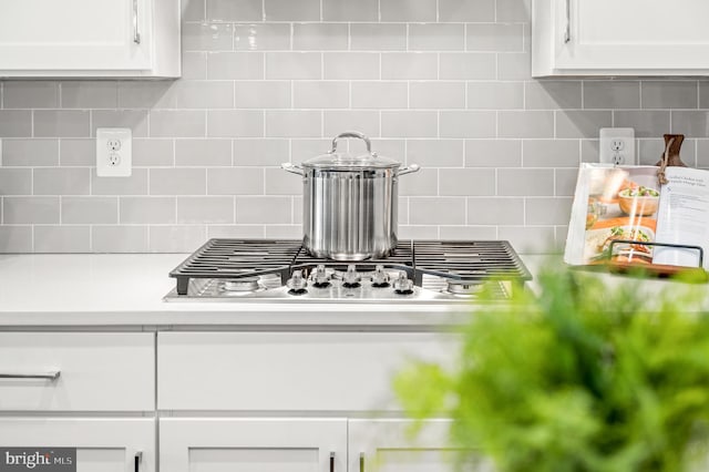 interior details with decorative backsplash and white cabinets