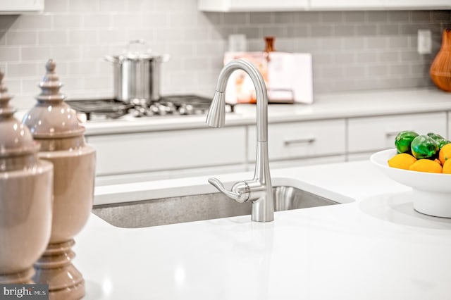 details featuring white cabinets and backsplash