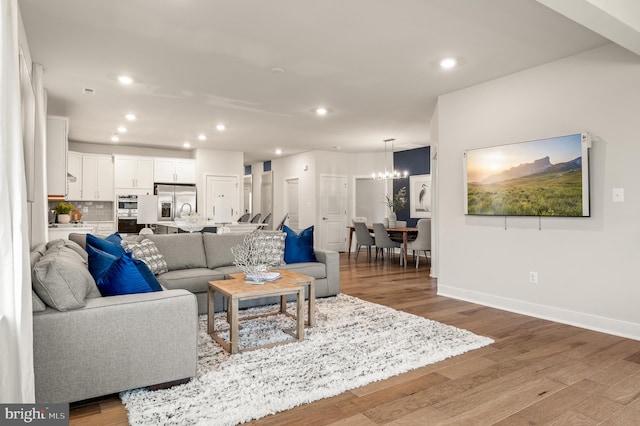 living room with light hardwood / wood-style floors and a notable chandelier