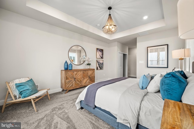 carpeted bedroom with a raised ceiling, a closet, and a notable chandelier