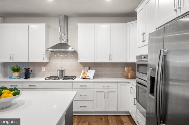 kitchen with white cabinets, wall chimney range hood, stainless steel appliances, and dark wood-type flooring