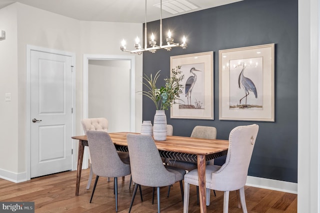 dining space with wood-type flooring and an inviting chandelier