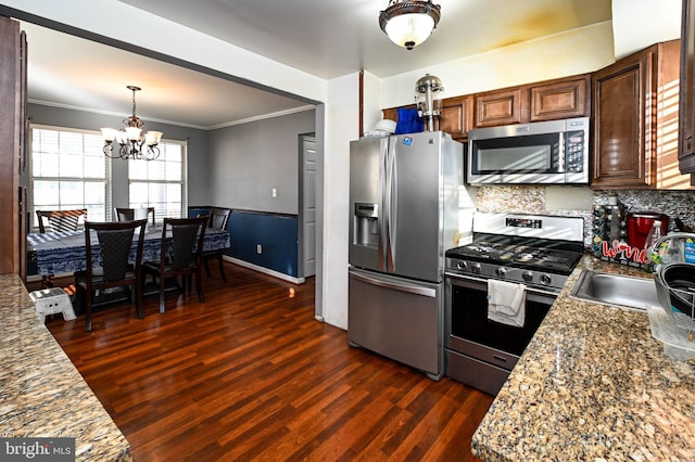 kitchen with stainless steel appliances, crown molding, dark wood-type flooring, a notable chandelier, and stone counters