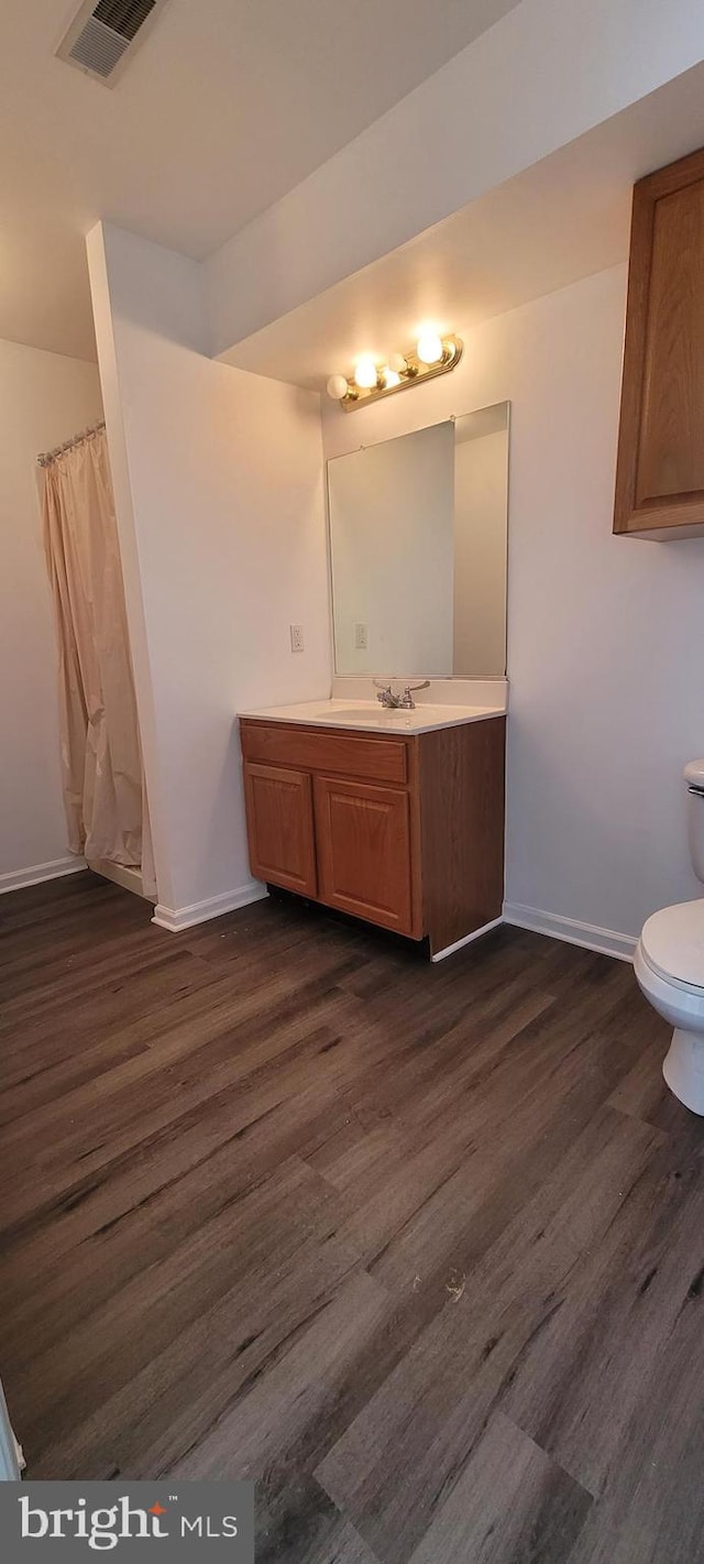 bathroom with hardwood / wood-style floors, vanity, and toilet