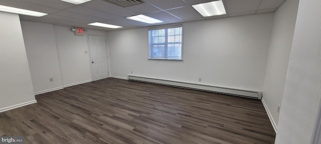 unfurnished room featuring a paneled ceiling, dark hardwood / wood-style flooring, and a baseboard heating unit