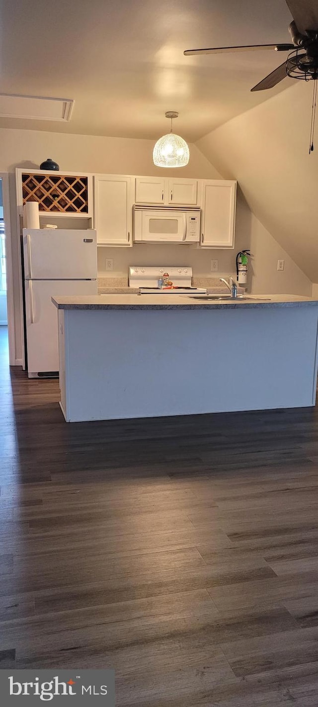 kitchen with white appliances, dark wood-type flooring, hanging light fixtures, vaulted ceiling, and white cabinetry