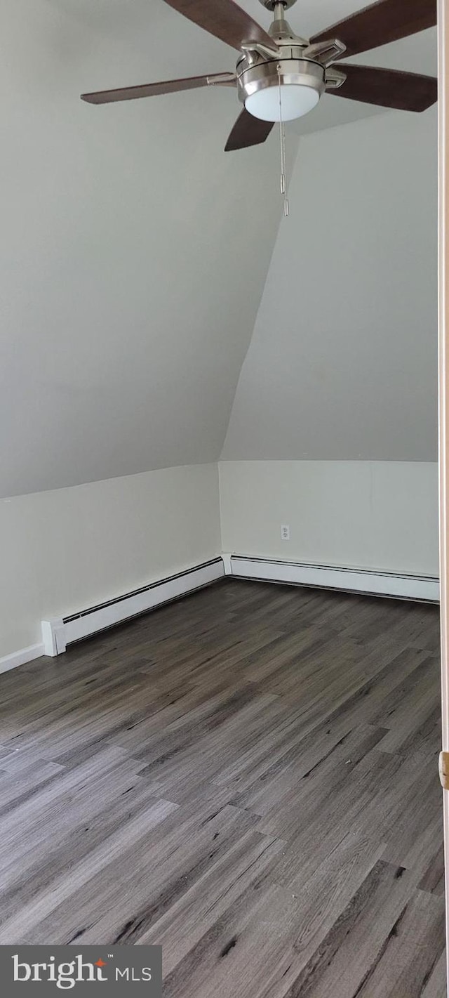 additional living space featuring dark hardwood / wood-style floors, ceiling fan, a baseboard radiator, and vaulted ceiling