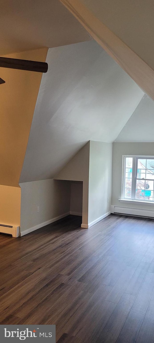 additional living space featuring a baseboard radiator, vaulted ceiling, and dark wood-type flooring