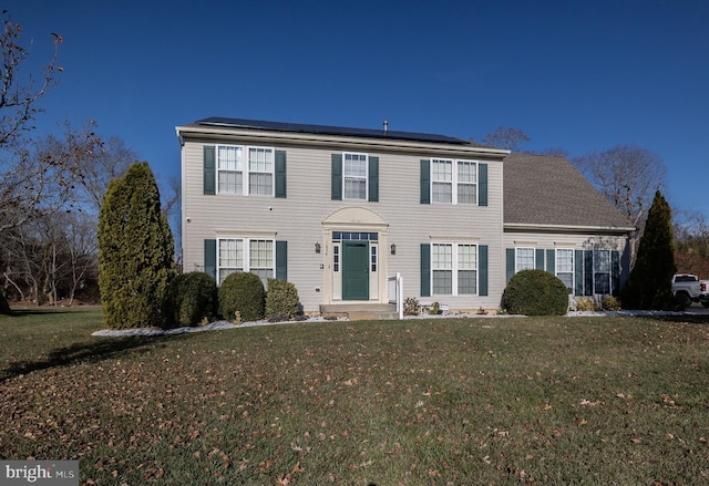 view of front of home featuring solar panels and a front lawn