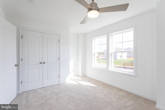 unfurnished bedroom featuring ceiling fan, light carpet, and a closet